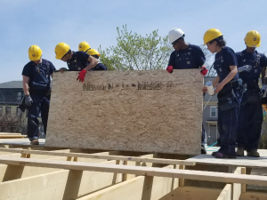 kids lifting wood at habitat for humanity job site